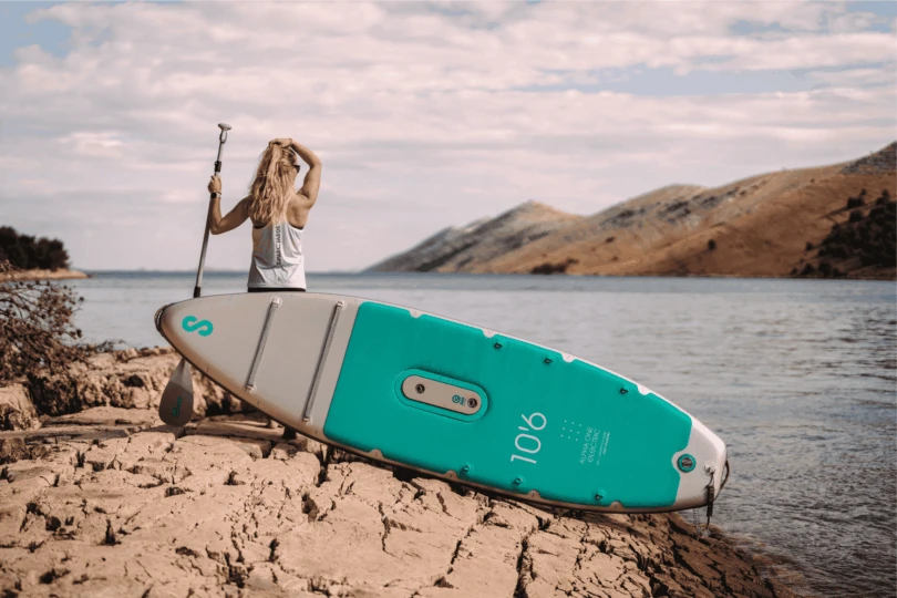 person stands next to SUP on land