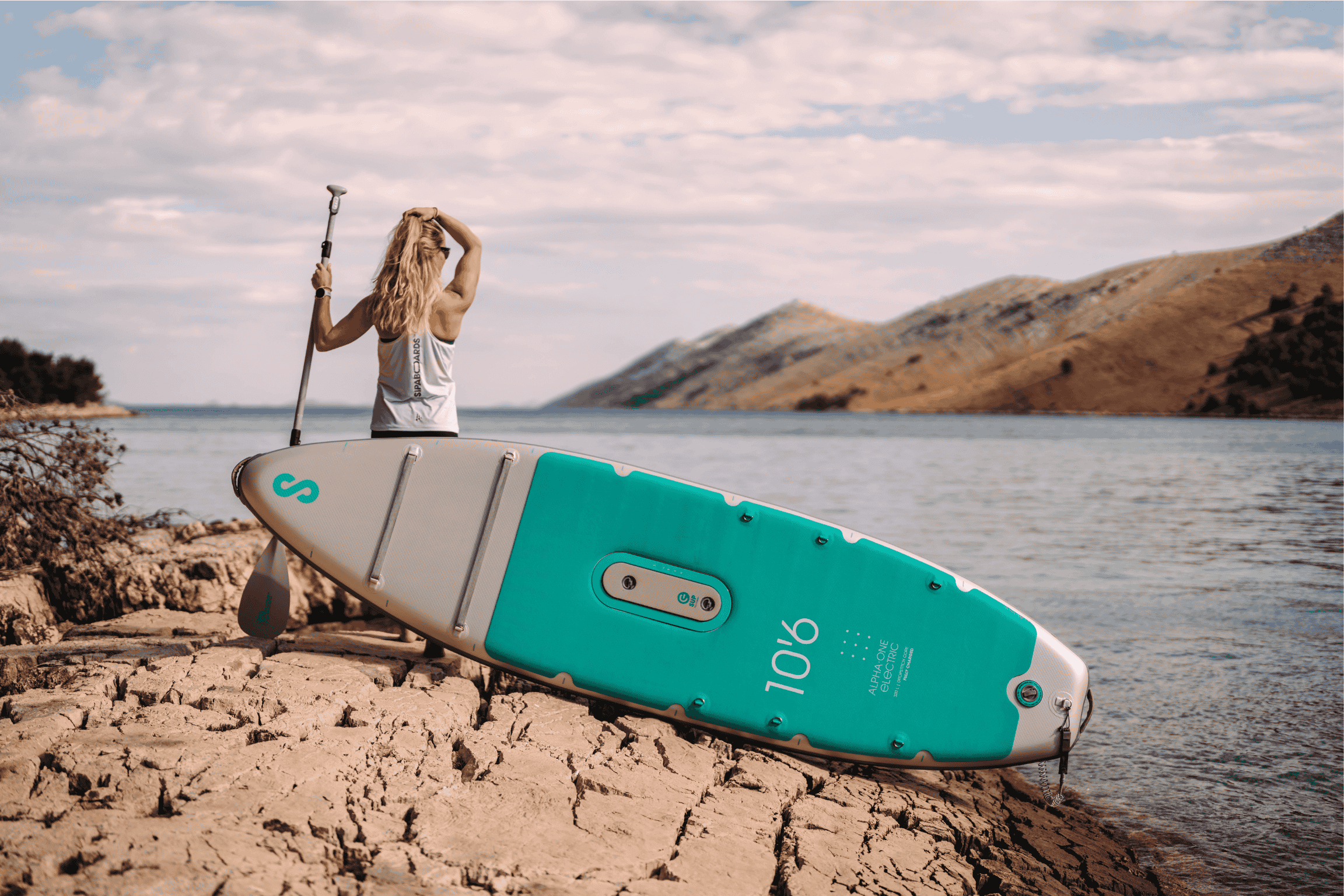 person stands next to SUP on land