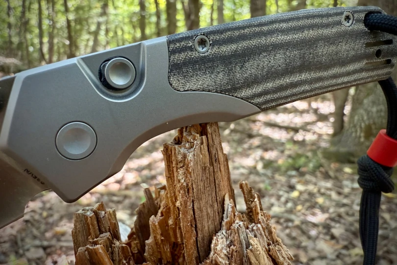 Close-up of the button lock and textured handle resting on a split tree stump