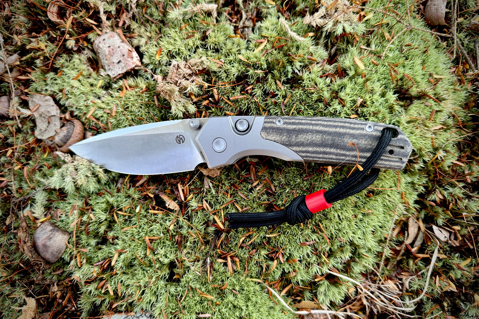 Full view of the knife lying open on green forest moss