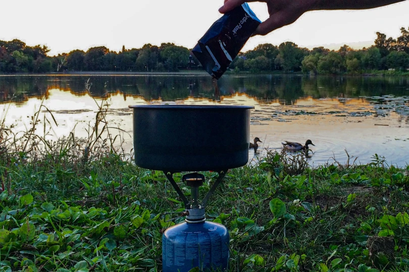 pouring coffee into pot on camp stove