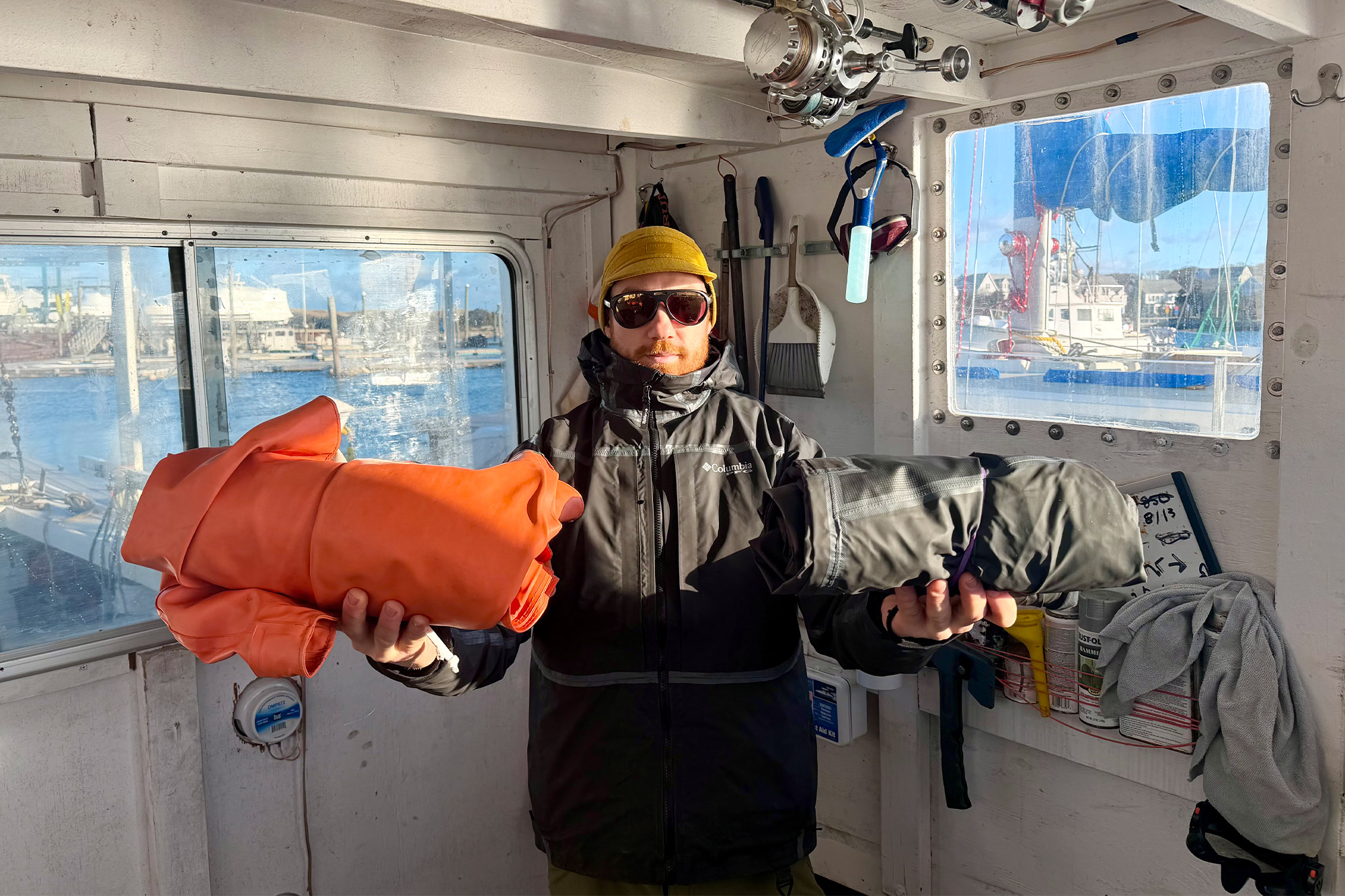 A fisherman holding the Columbia PFG Force XII ODX Bib and Jacket to compare packed size