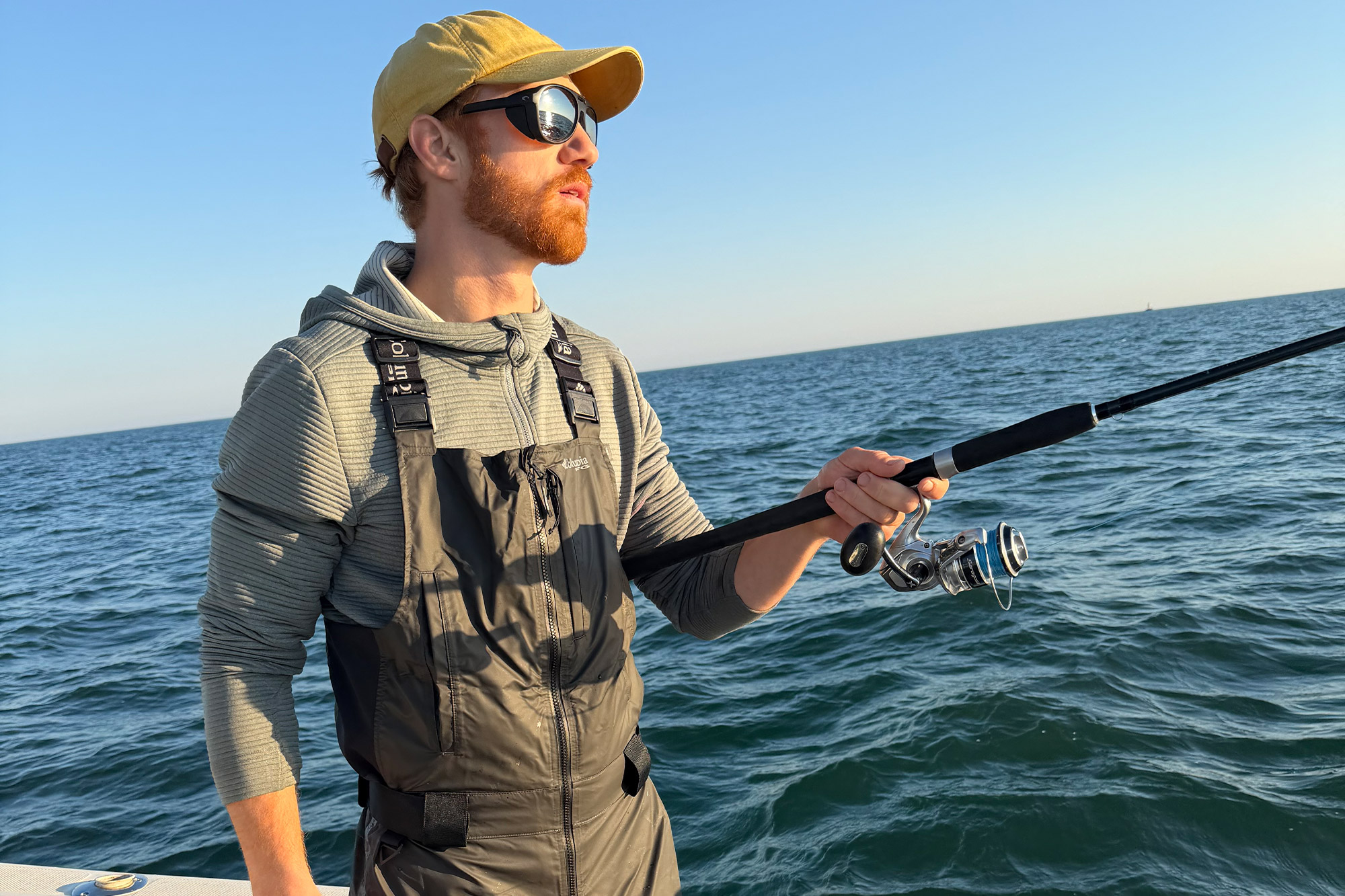 A fisherman wearing the Columbia PFG Force XII™ ODX Bib while fishing on open water from a boat