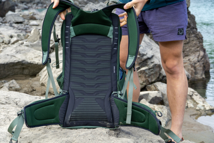 one of the gearjunkie testers shows the back panel of an osprey daypack beside a lake in washington state