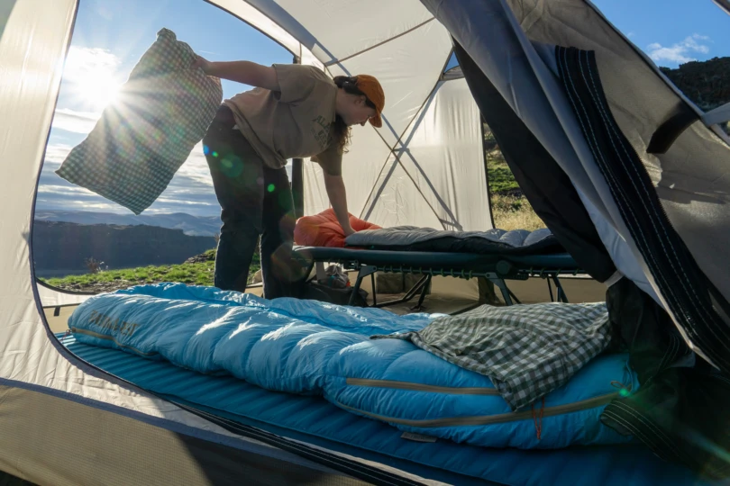 a camper organizes the inside of a tent with the mondoking 3d mattress and a camping cot set up