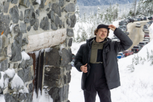 Senior Editor Nick Belcaster testing winter jackets standing next to stone building with snowy backdrop