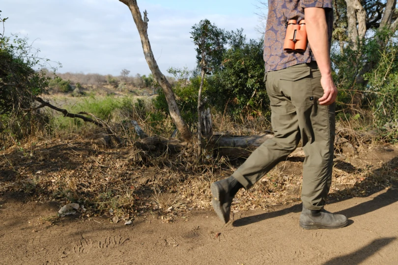 the author walking on a trail in africa wearing the layover pro traveler pants