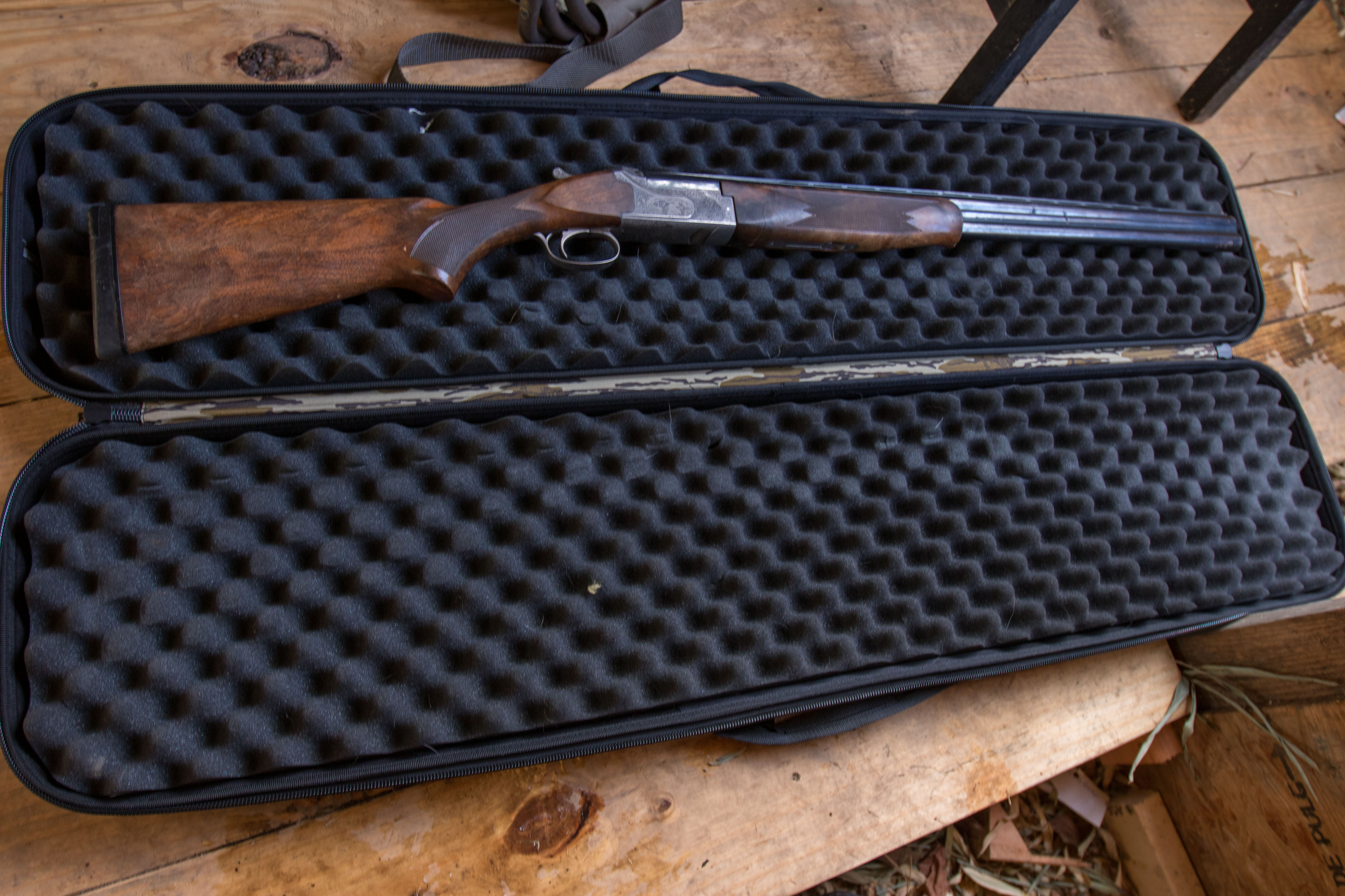 The Plano Diverge Gun Case opened up in a duck blind with an Over/Under shotgun inside.