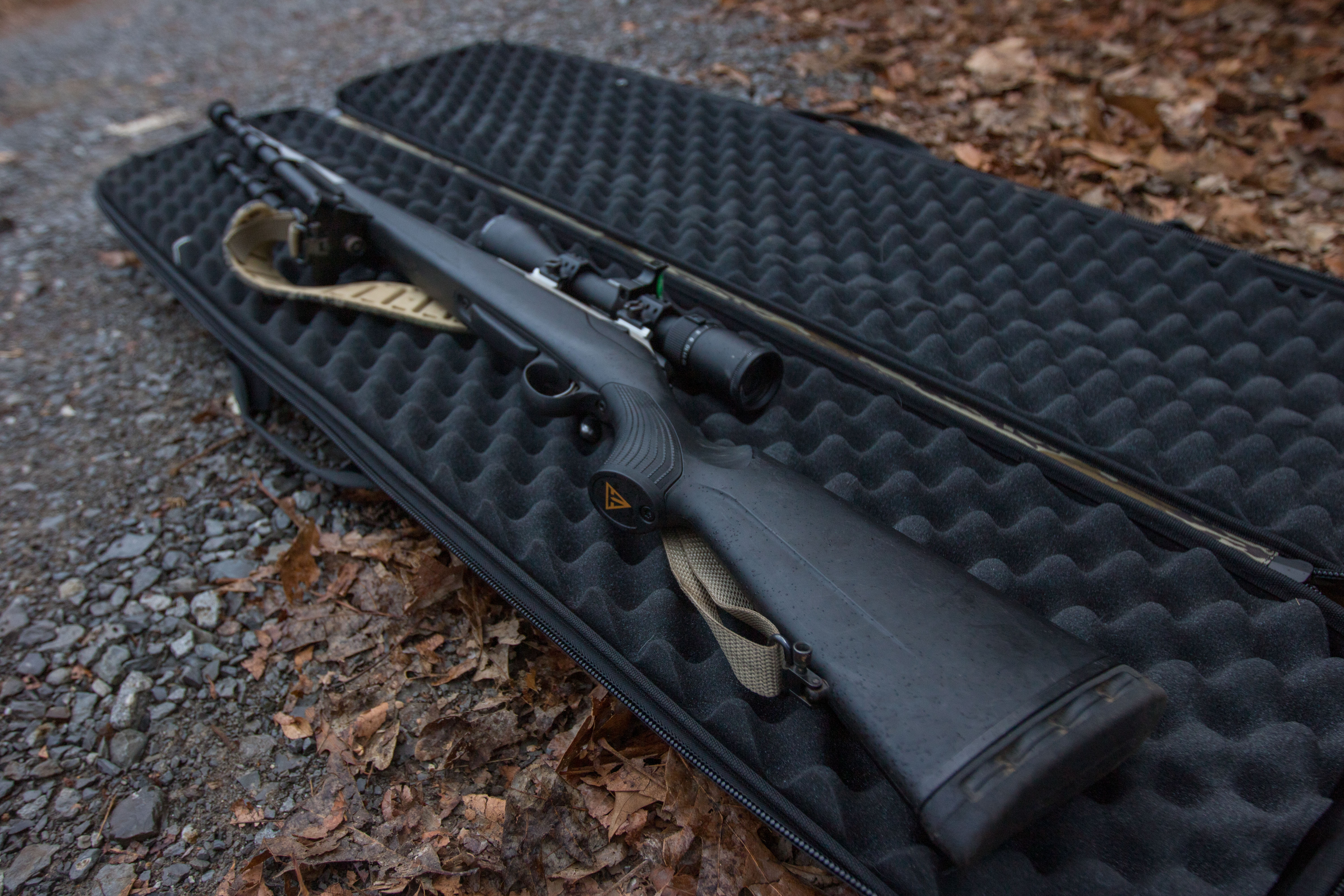 A Tikka rifle lying in a gun case on the ground.