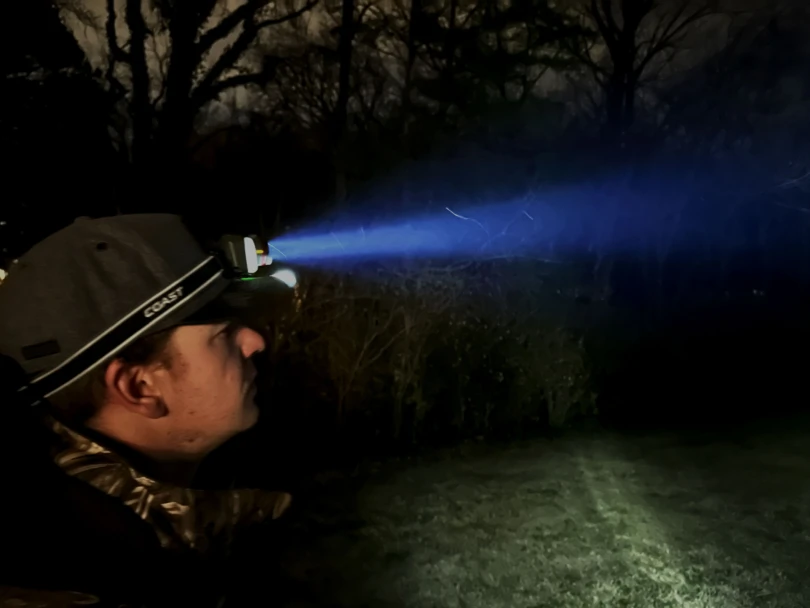 A hunter wearing a headlamp in the dark with the beam shining forward.