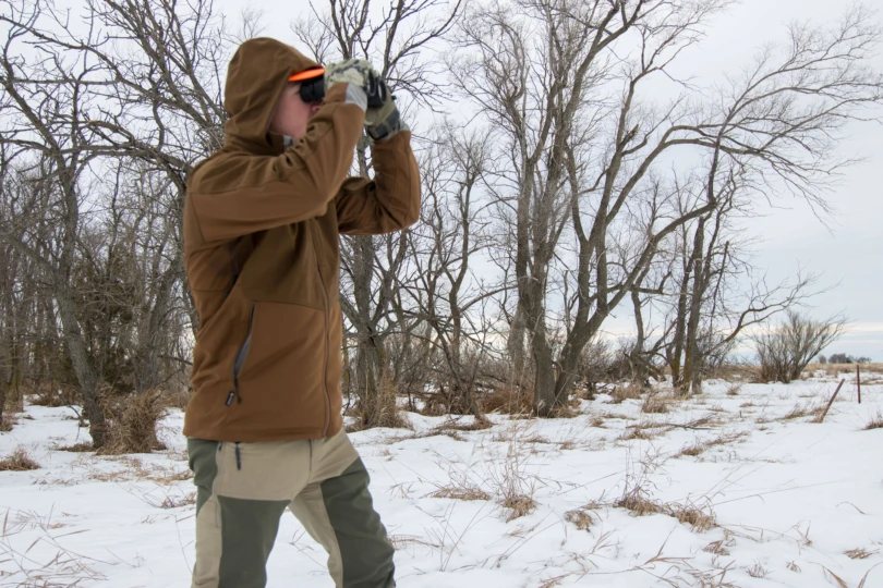 A hunter glassing a winter landscape.