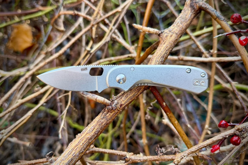 The Lander 5 knife balanced on dry branches with the blade open