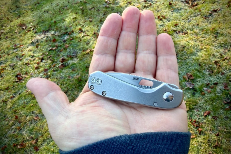 The compact Lander folder resting in an open hand outdoors