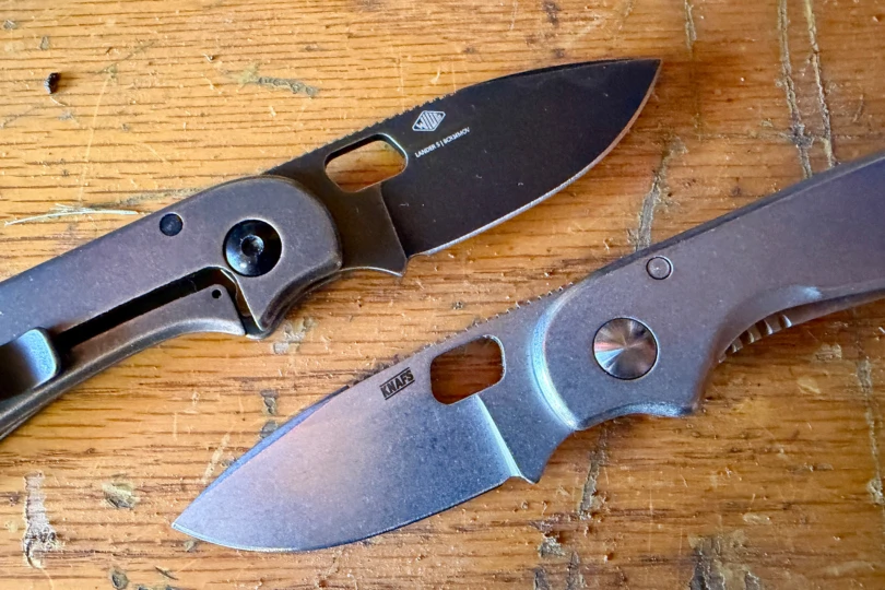 Both versions of the Lander knife shown on a workbench with their blades open
