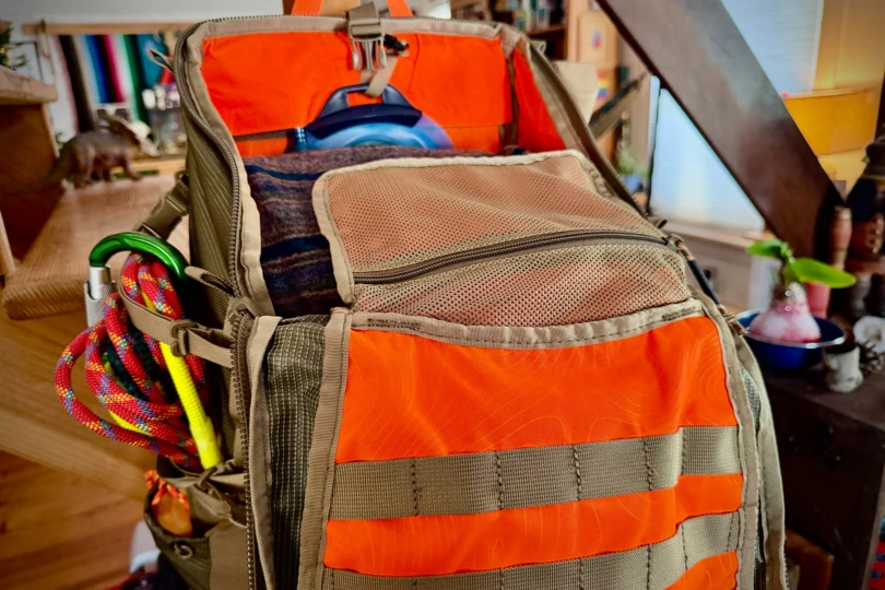 Open main compartment of the backpack showing mesh pocket and packed clothing