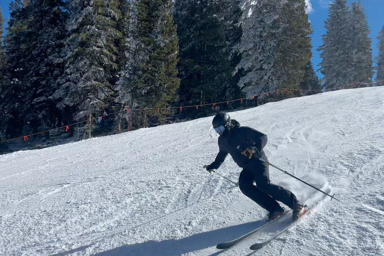A skier carving downhill wearing the Lofoten jacket and pants