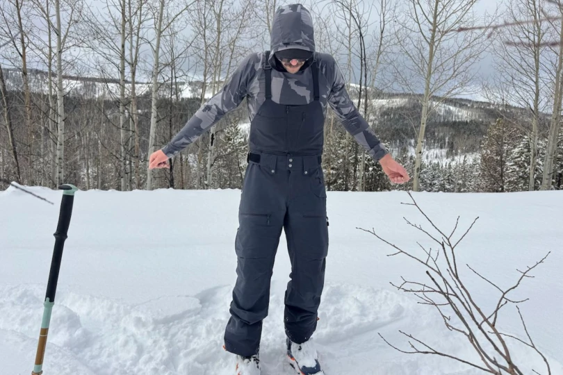 A skier standing in deep snow wearing Norrona Lofoten Flex1 jacket and pants