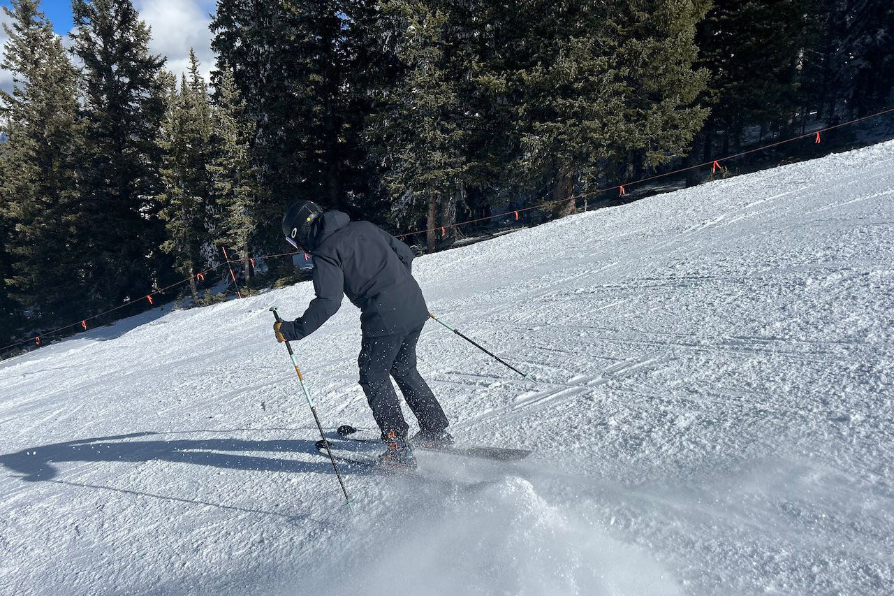 A skier turning downhill while wearing the Norrona Lofoten Flex1 pants and jacket