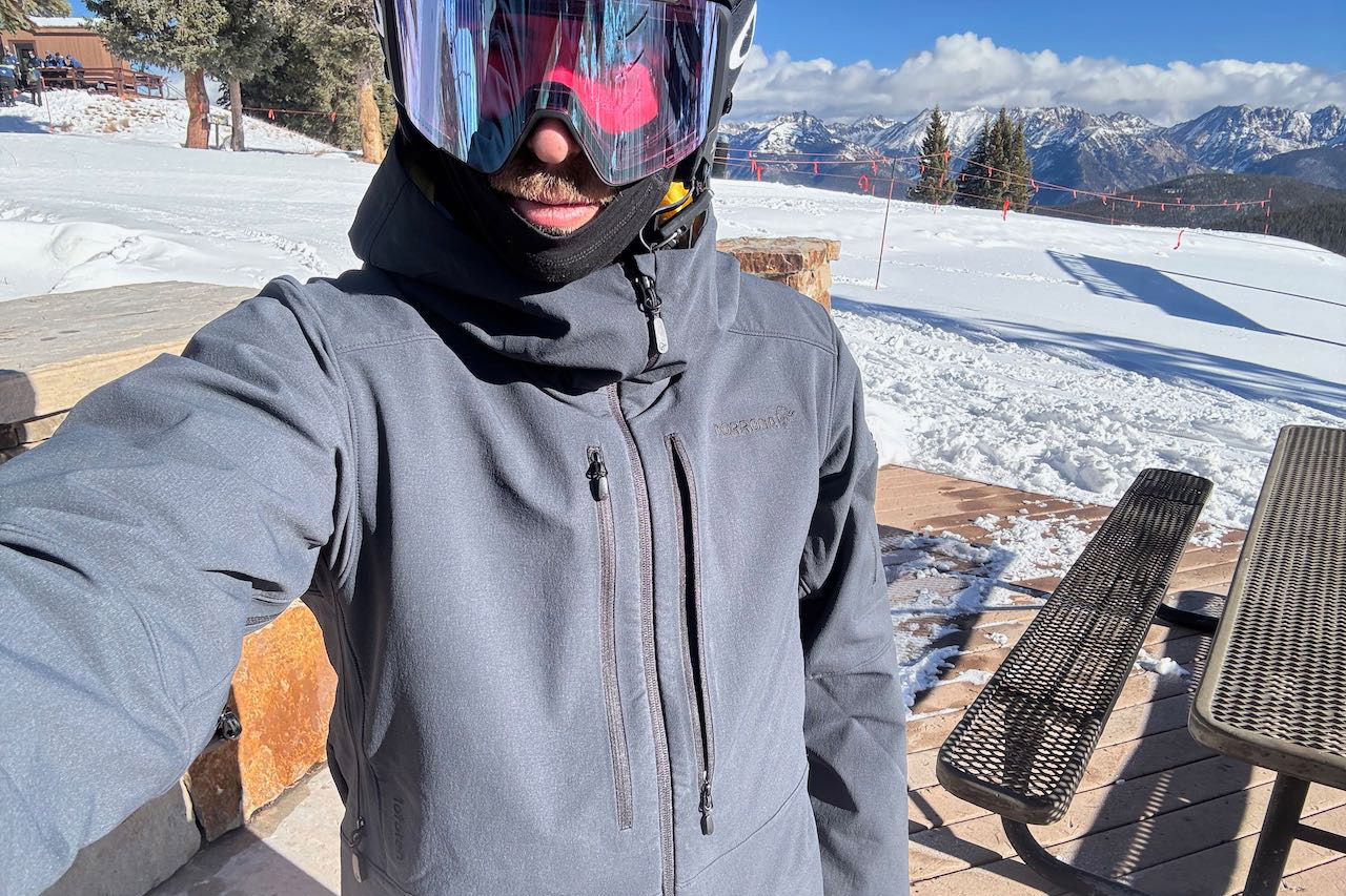 Front view of the Norrona Lofoten jacket worn with goggles at the ski resort