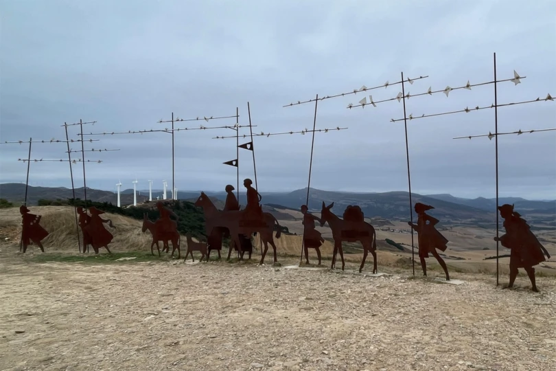 Metal pilgrim silhouettes on a windy ridge along the Santiago walk