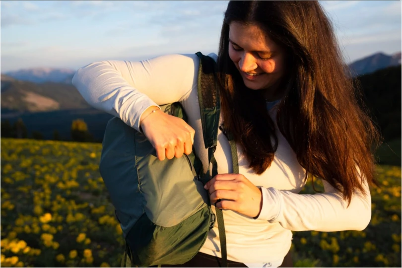 a hiker accesses the rear pocket on the flash 18 pack