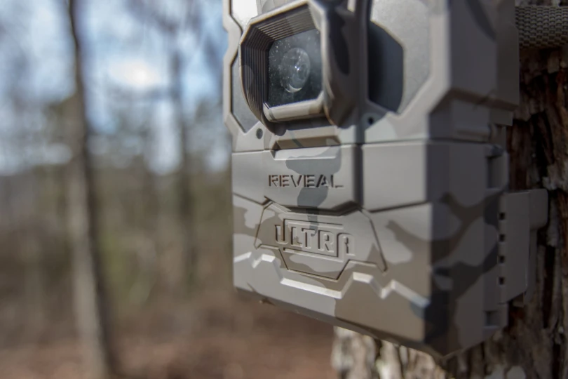 The best overall trail camera of 2025, the Tactacam Reveal Ultra hanging on a tree.