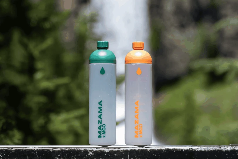 two water bottles in front of a waterfall