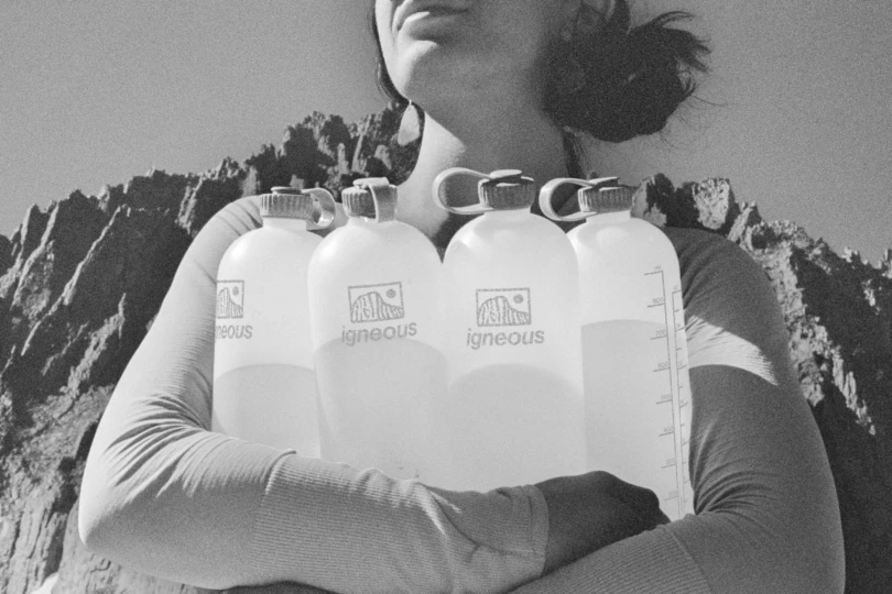 black and white photo of person holding a bunch of resusable Igneous water bottles