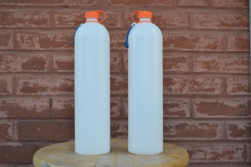 two reusable water bottles with brick wall behind