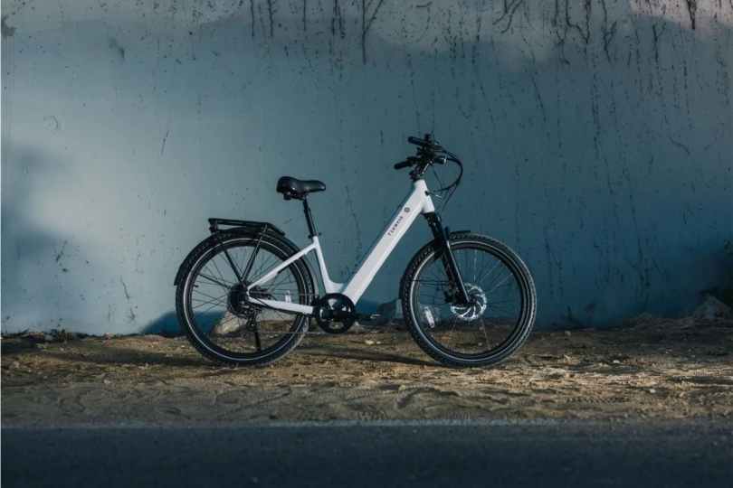 white e-bike standing on dirt in front of concrete