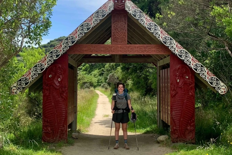 backpacker stands in front of wooden gate