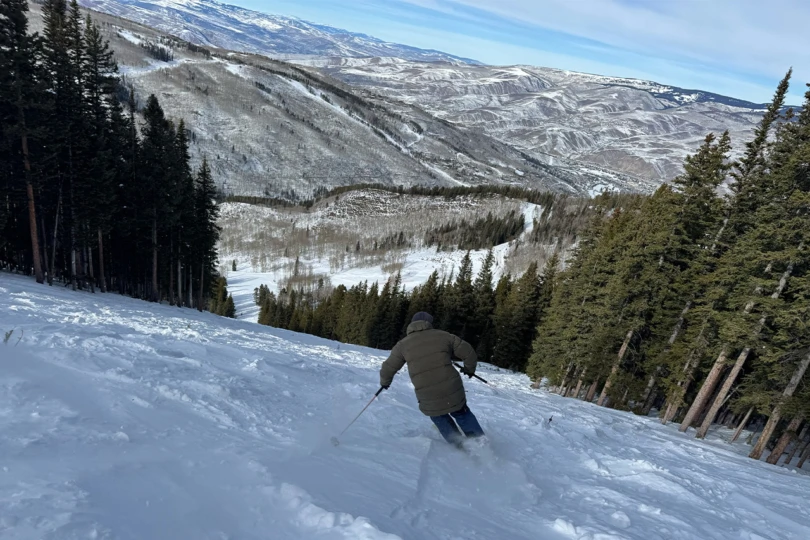 A skier rides the Völkl Revolt 101 while spraying snow during a turn