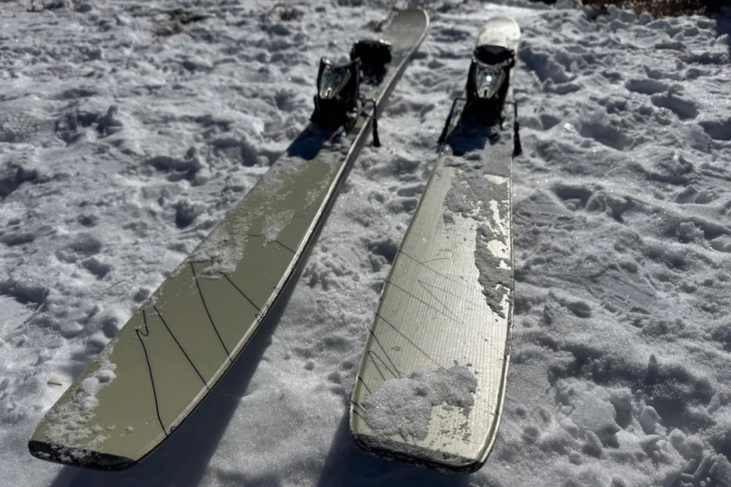 The Völkl Revolt 101 skis are laid flat on packed snow with bindings mounted