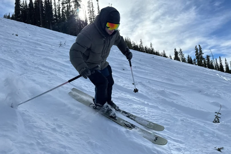 A skier uses Revolt skis while descending a wide, snowy run