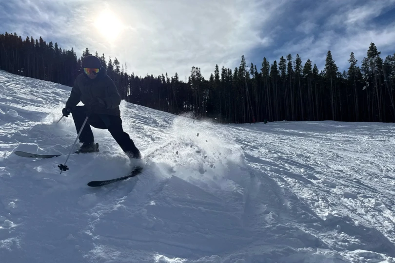A top-down view shows Revolt skis on packed snow with boot shadows