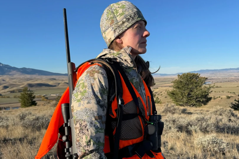 A woman wears a women’s AllClima soft shell jacket while standing on open terrain