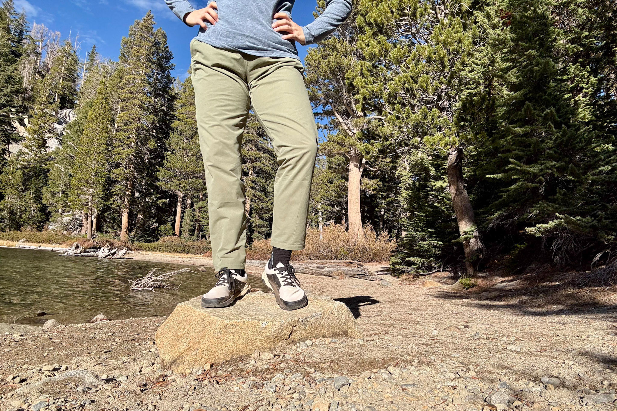 Yama shoes worn with hiking pants beside a calm lake