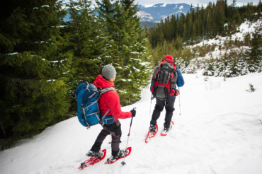 Two,Climbers,With,Backpacks,And,Snowshoes,Are,On,The,Snow