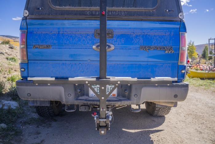 A rear-mounted bike rack attached to a blue pickup truck.