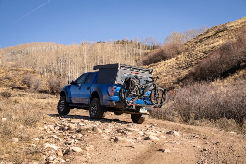 The truck drives a rocky road with two bikes mounted on the rack