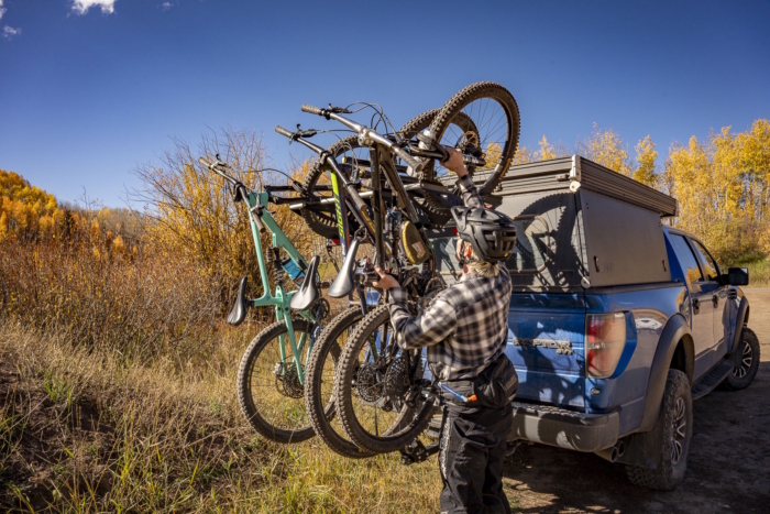 A person loading mountain bikes onto a truck rack