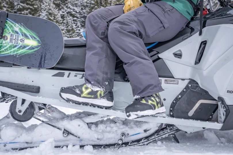 Person wearing insulated snow boots while sitting on a snowmobile