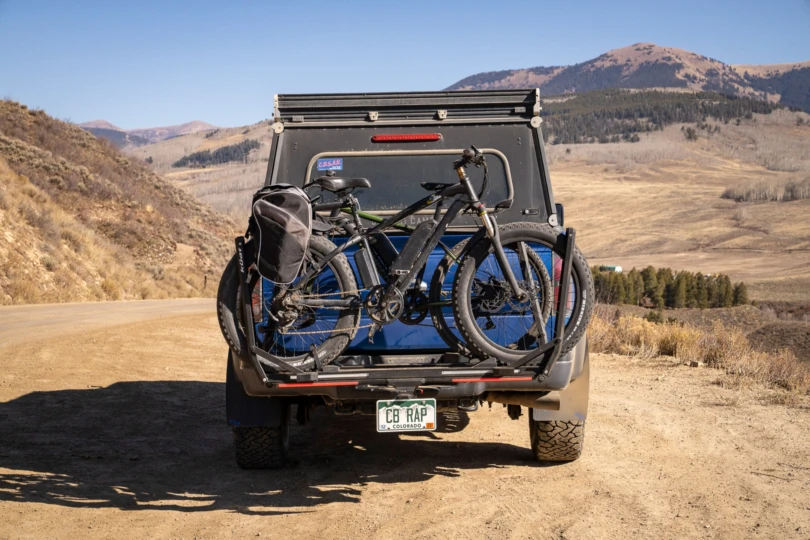 Two bikes sit mounted on the rack with open mountain views behind
