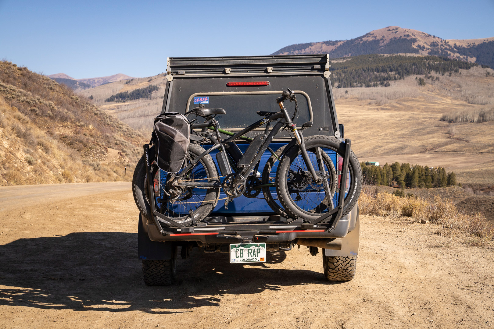 Two bikes sit mounted on the rack with open mountain views behind