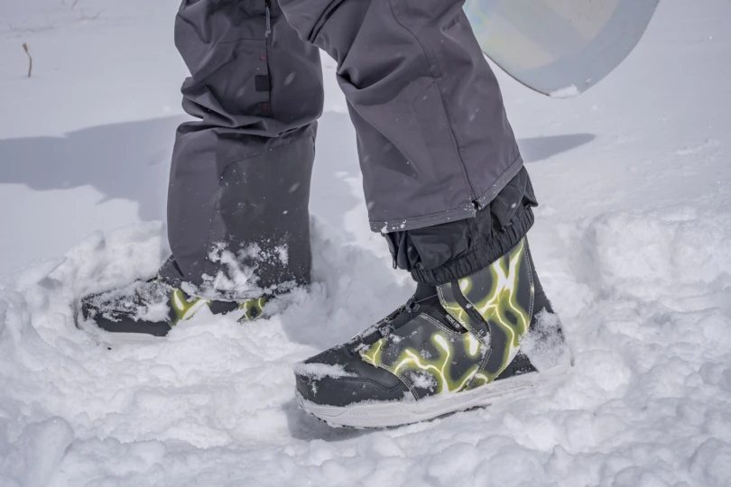 Person wearing snow boots standing in deep snow outdoors.
