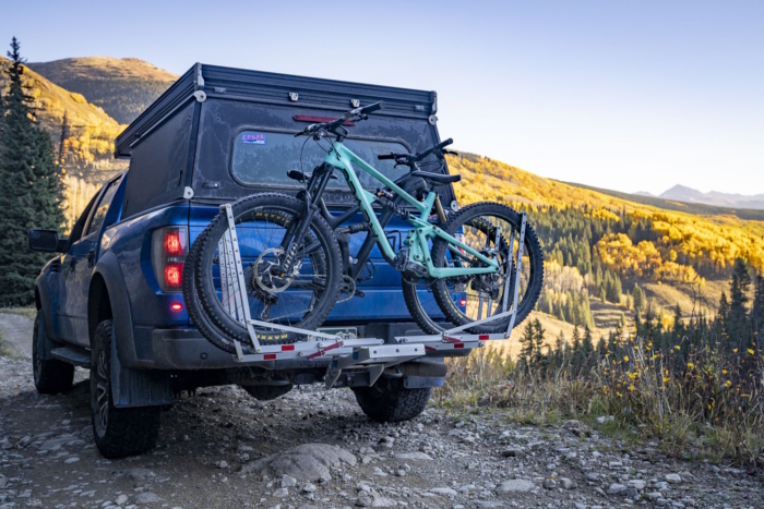 Blue pickup truck, carrying two teal mountain bikes on a heavy-duty hitch rack