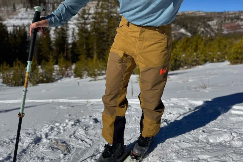 Helly Hansen Emiko Shell Pants worn while standing on packed snow, showing the front fit and lower leg panels