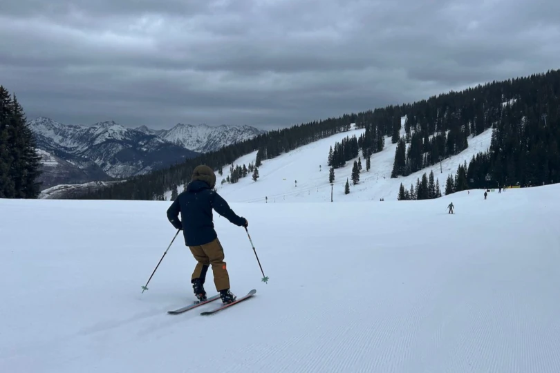 Skier wearing Helly Hansen Emiko Shell Pants moving across a wide groomed ski run