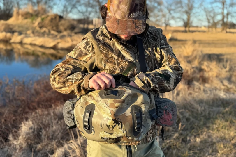 Person opening the main zipper on the KUIU DeltaStorm 800 Submersible Waistpack