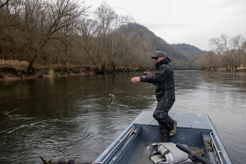 An angler lifting a trout into the boat with the Shimano Compre Light Spinning Rod.